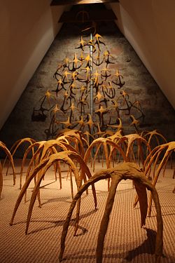 Kunstobjekt: Viele, gelbe Insekten aus Papier, klettern die Wand nach oben.