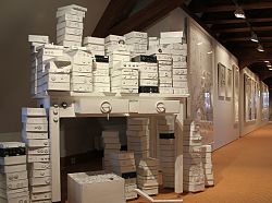 Objektkunst aus Papier. Auf dem Bild ist ein Tisch mit vielen Papierkisten zu sehen.